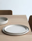 Top view of Forme Collection large stoneware plate in sand tone, showing glazed interior and unglazed exterior